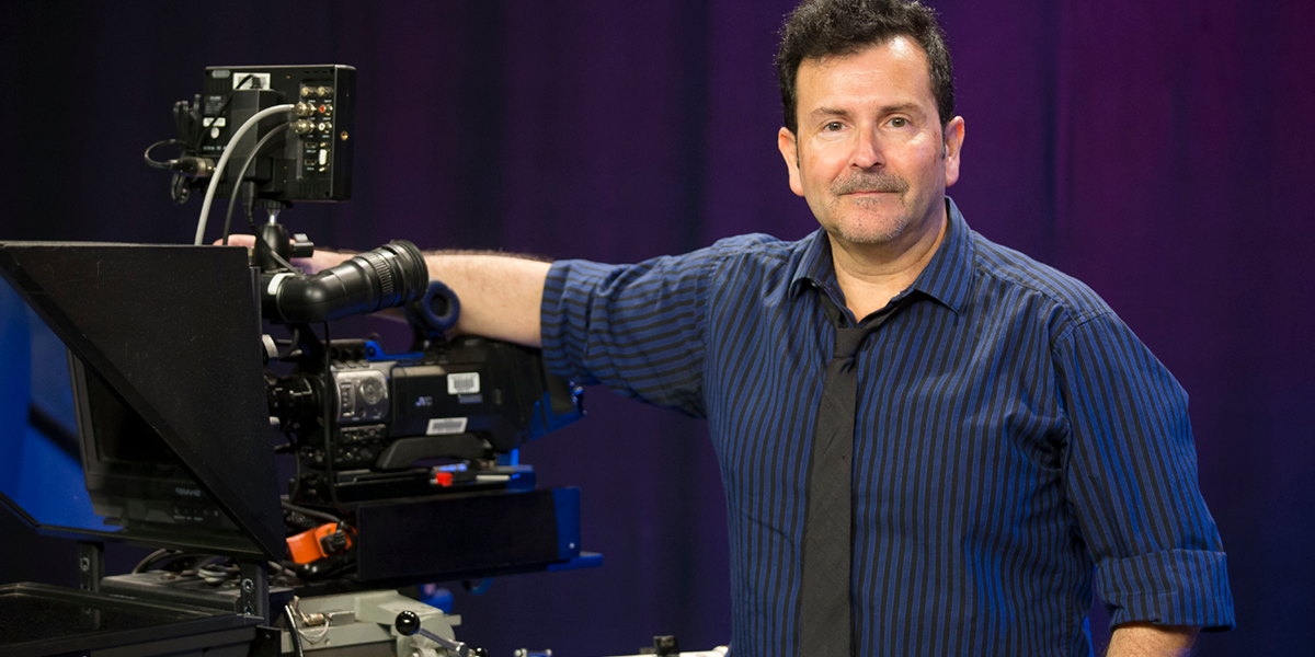 Photo of Len Haynes standing next to video camera and lighting equipment