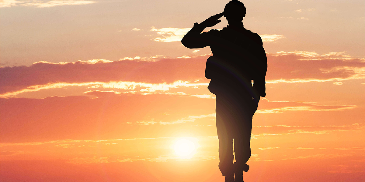 Photo of sillhouette of soldier saluting in front of a sunset
