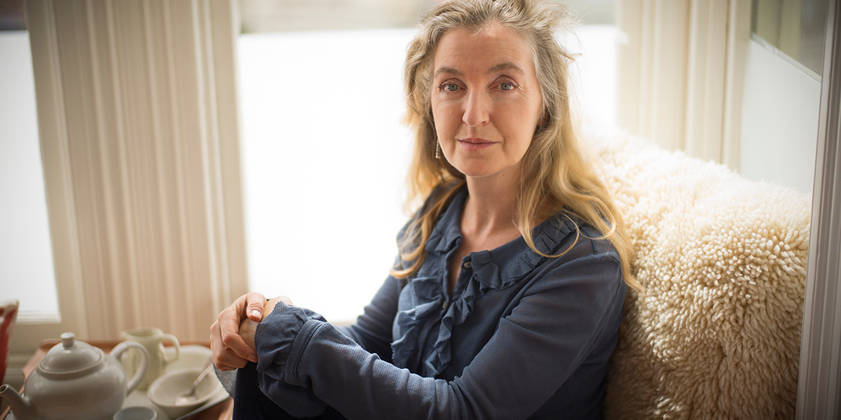 Photo of Rebecca Solnit seated near coffee table with tea kettle and cups