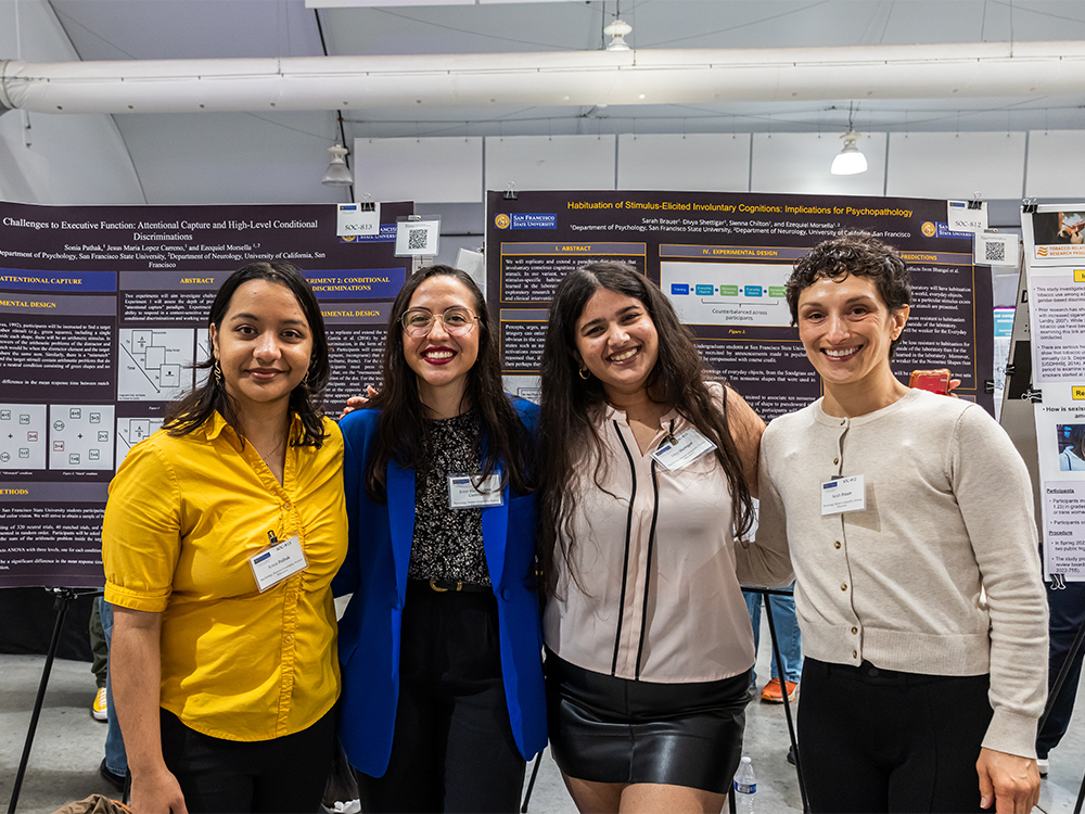 Four students standing in front of their research posters at CoSE showcase