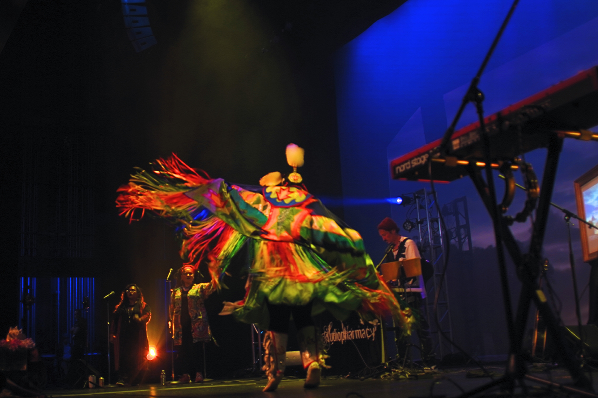 performer wearing colorful indigenous garment dances on stage