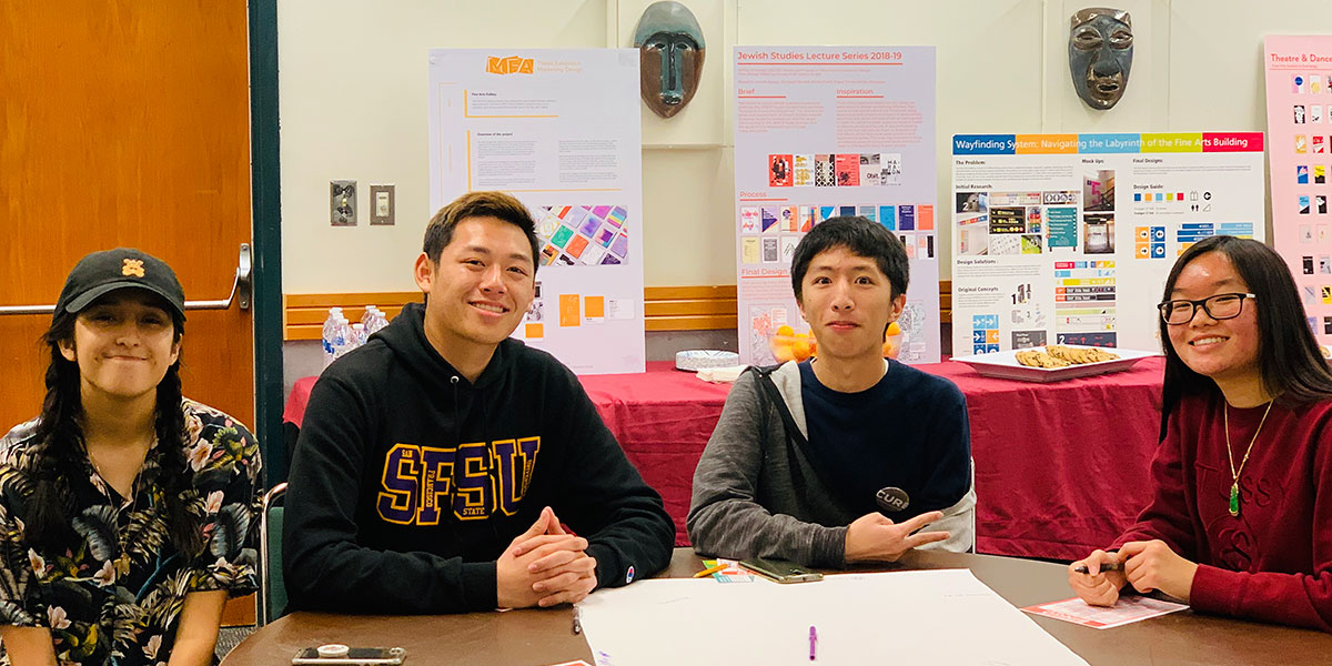 Four students sitting at table facing foward