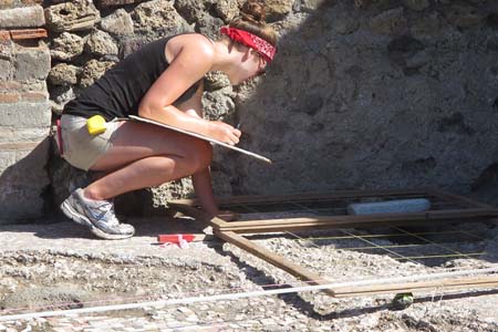 Student examining artifact at dig