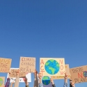 Hands holding up climate change signs against blue sky