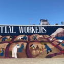 A mural depicting a boy sleeping under a quilt that depicts various essential workers accompanied by text Thank You Essential Workers