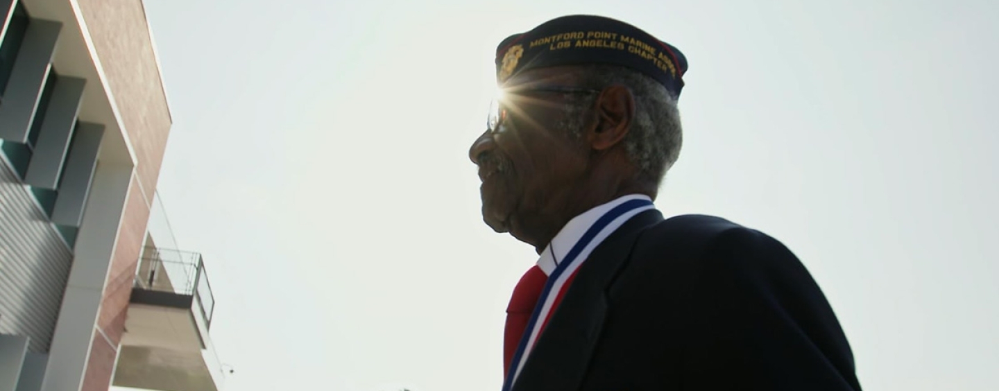 Henry Charles Johnson, a veteran and member of the Monford Point Marines, walks outdoors in uniform on a sunny day