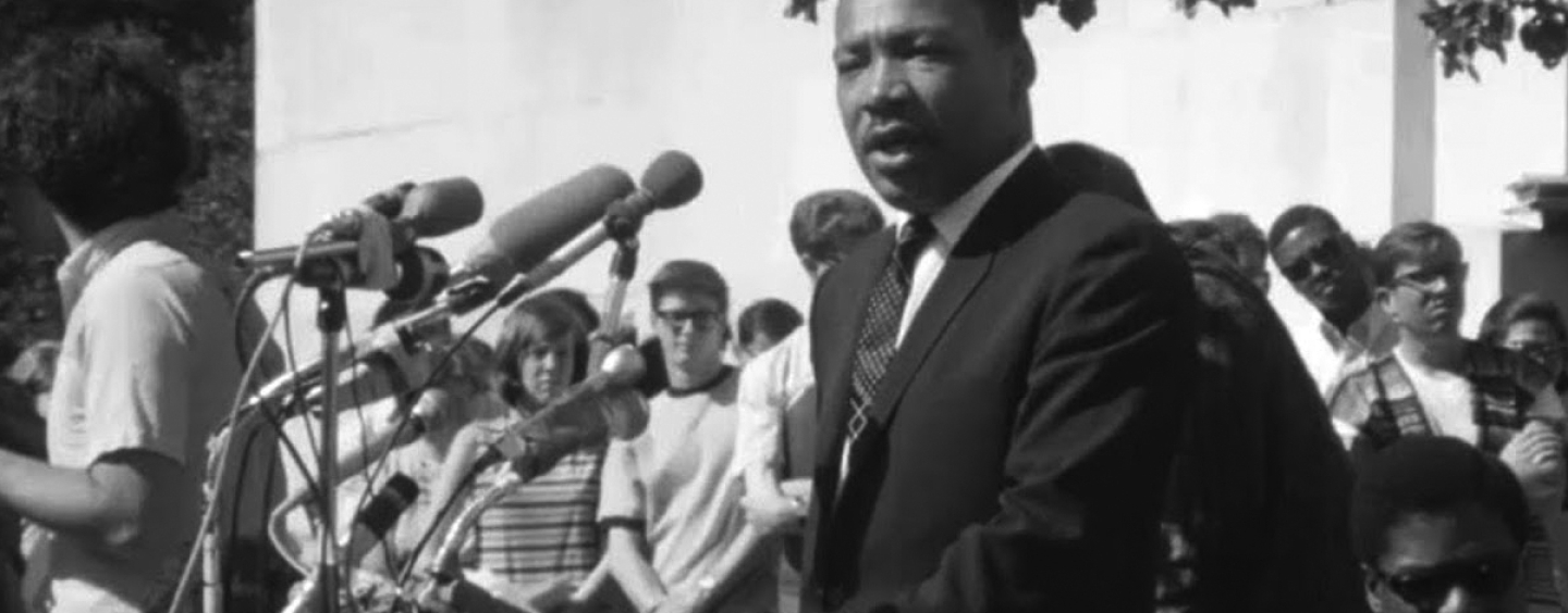 The Rev. Martin Luther King Jr. speaks in front of a podium with about 10 microphones attached to it