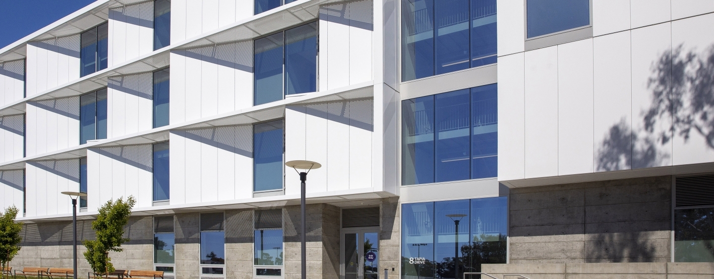 White and gray building with grass in front of it