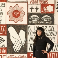 Liz Hernández standing in front her mural at the San Francisco Museum of Modern Art