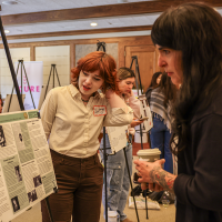 Student showing faculty her research poster at LCA research showcase