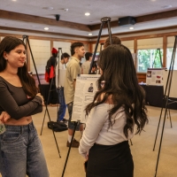 Two students talking in front of a project on an easel.