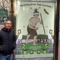 Marcelo Potosi stands on Market Street next to his Revitalizing the Culture poster for the series titled The Future of the Ramaytush Ohlone
