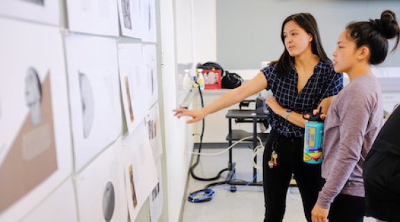Student gesturing to diagrams on wall