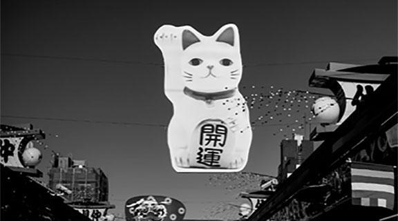 Cat sculpture with mandaring lettering hanging from wires above street
