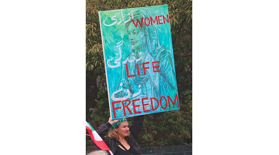Woman holding sign that says Women. Life. Freedom.
